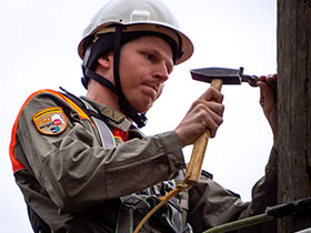 Ein Führungsunterstützer beim Einschlagen eines metallenen Kabelträgers